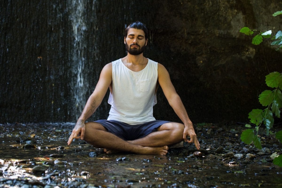 Man meditating outside by a waterfall in Minneapolis, MN