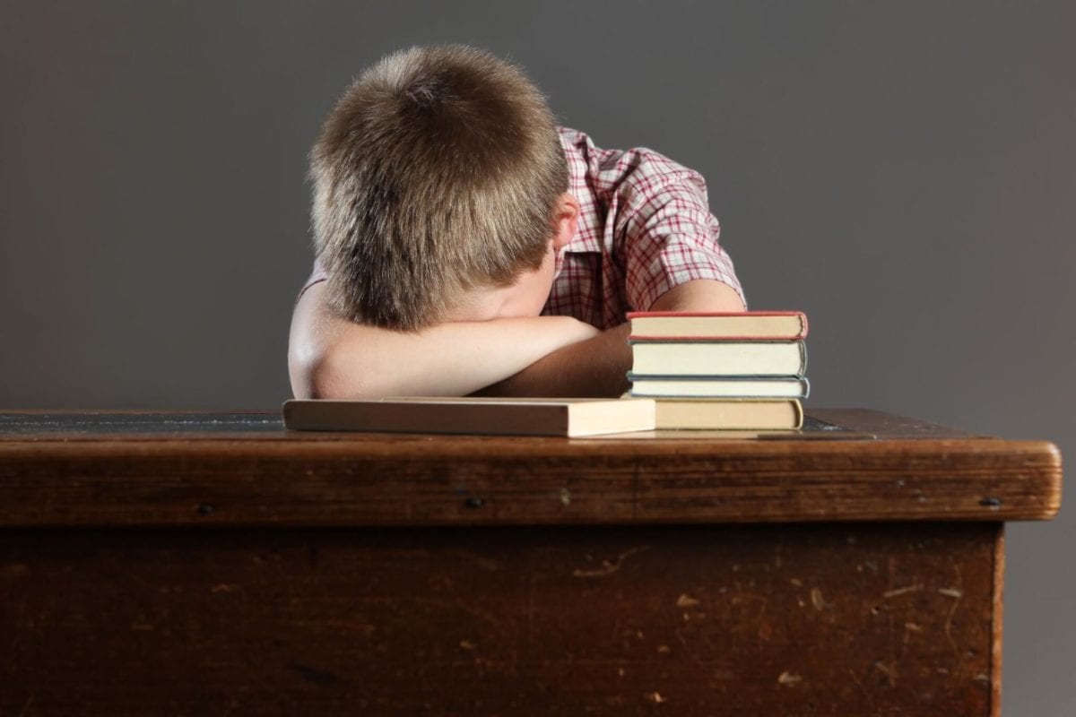 Boy who can't focus on school work with his head on his desk in St. Pual, MN